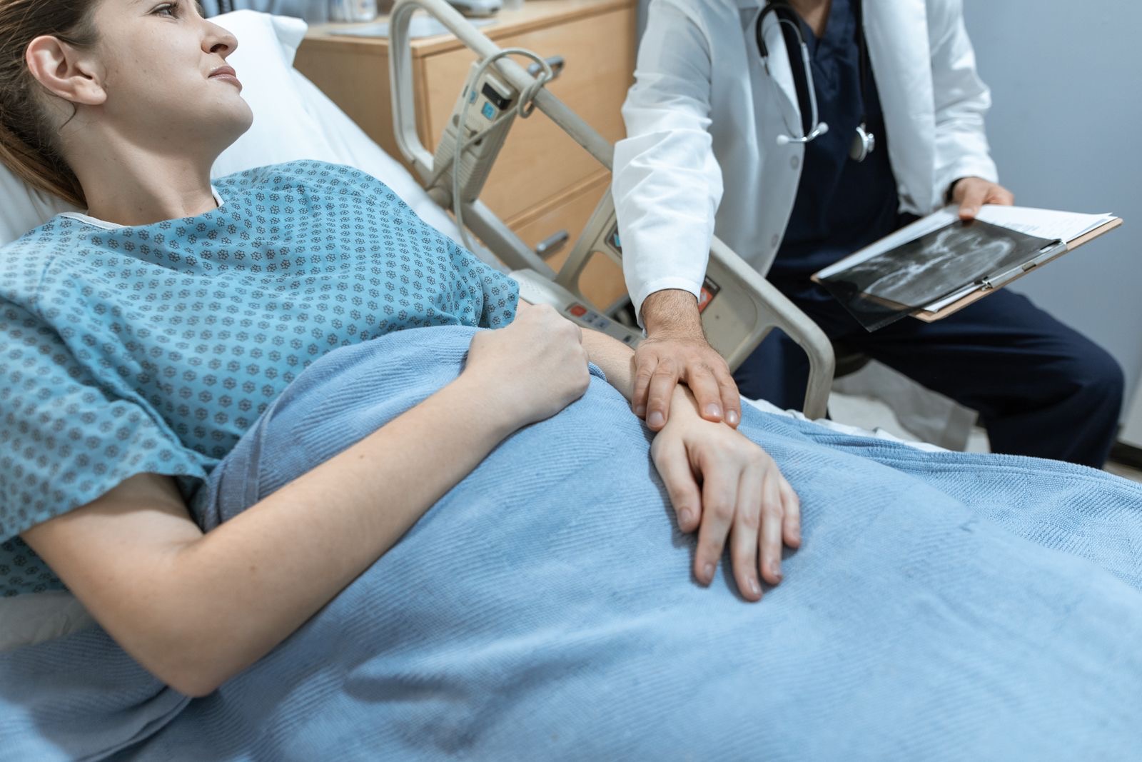 A clinician holding a patient's hand at the bedside